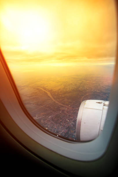 attraverso la finestra dell'aereo che sorvola il paesaggio - sundow foto e immagini stock