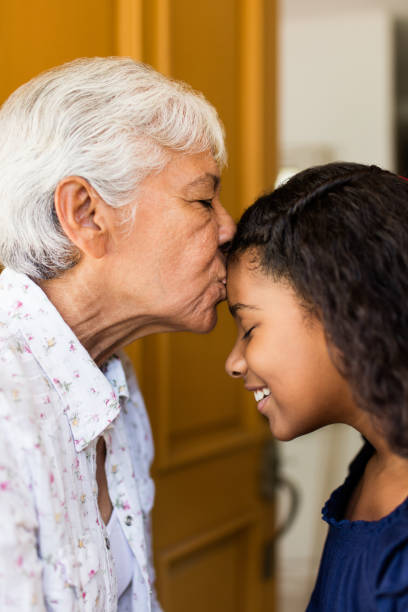 istock Affectionate grandmother kissing granddaughter on forehead 984477370