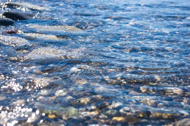 istock sea pebble beach with multicoloured stones, waves with foam 984486200