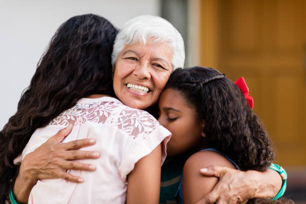 istock Grandmother embracing granddaughters and smiling 984486754