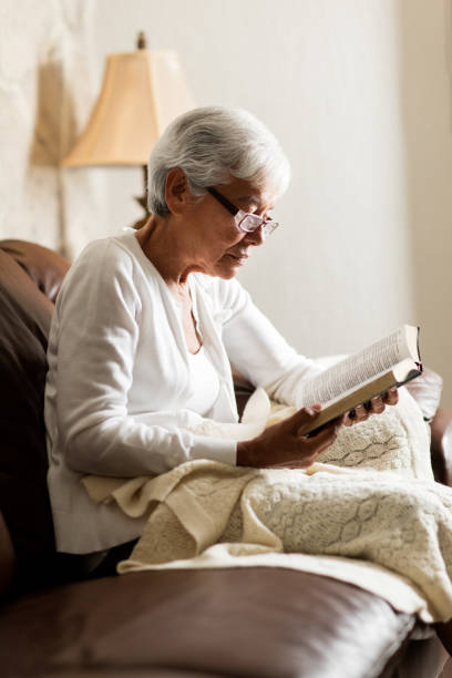 istock Senior latin woman sitting on sofa and reading 984492082