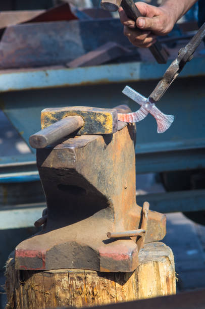 istock blacksmith performs the forging of hot glowing metal on the anvil 984503370