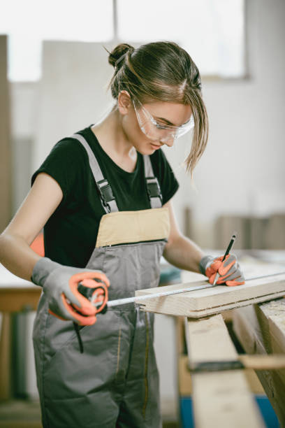 istock Female Carpenter Measuring Plank Length For Work 984506192