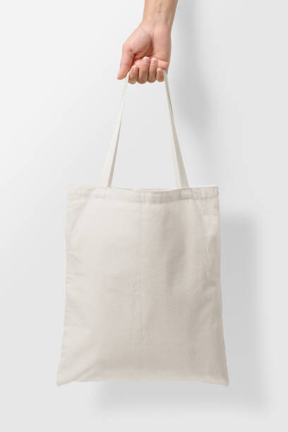 maquette de la main féminine tenant un sac en toile fourre-tout blanc sur fond gris clair. - tote bag photos et images de collection