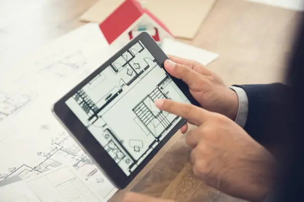 Real estate agent or architect presenting house floor plan to client on tablet computer screen