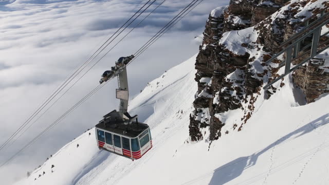 Cablecar ascends from valley bottom, winter snow