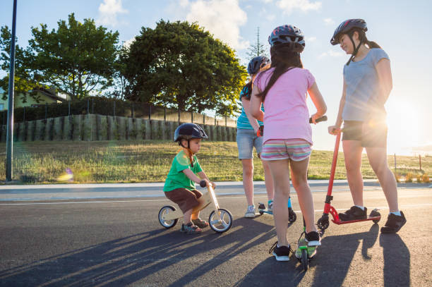 Siblings riding scooters and a balance bike stock photo