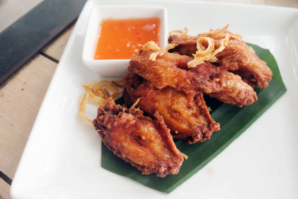 istock Fried chicken wings with sauce in white plate on wooden table. 984592616