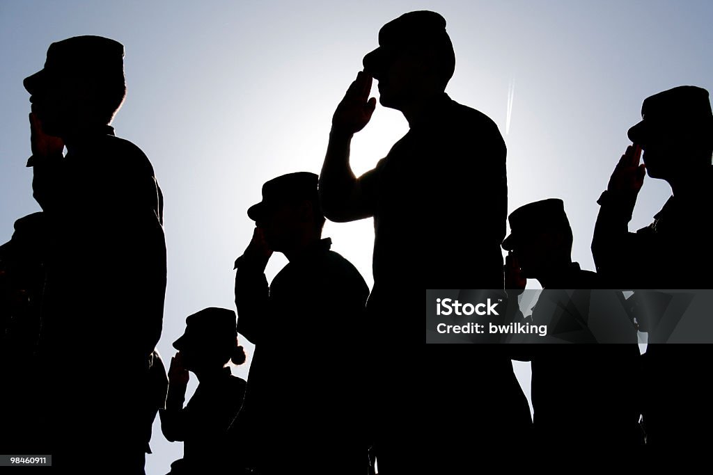Soldiers Salute the Flag at Sunset Several soldiers salute the flag at sunset during a military exercise. Army, Marines and Air Force were represented at the ceremony.  Military Stock Photo