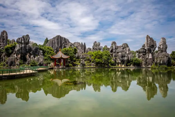 China - East Asia, Stone Forest - Kunming, Yunnan Province, Clear Sky, Copy Space. The Stone Forest or Shilin  is a notable set of limestone formations. The tall rocks seem to arise from the ground in a manner somewhat reminiscent of stalagmites, or with many looking like petrified trees, thereby creating the illusion of a forest made of stone. Since 2007, two parts of the site have been UNESCO World Heritage Sites as part of the South China Karst.