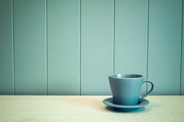 istock Green mug on wooden table over green background 984629022