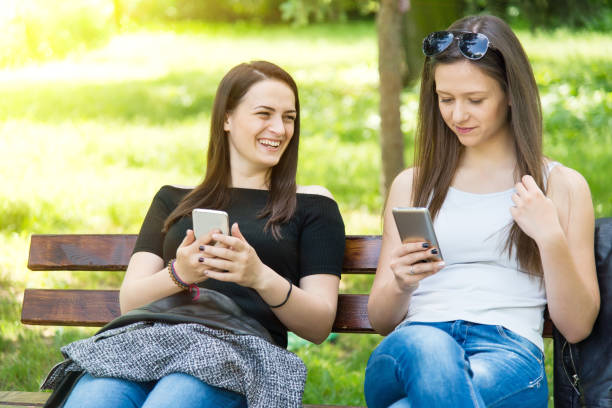 istock Two beautiful girls in the park surf the web. 984629076