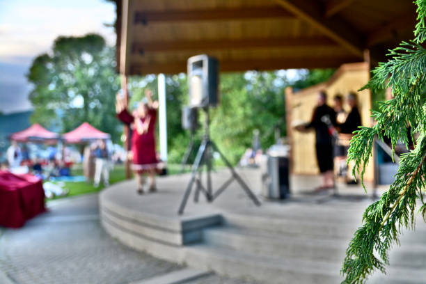Port Moody, British Columbia, Canada - June 21, 2018: The Aboriginal performers recreate traditional dances by their ancestors on the Pacific Coast Terminal Stage, Rocky Point Pier on National Indigenous People's Day, 2018. Male dancers, other performers and the local residence of Port Moody watch then applaud. The focus is limited to a fir bow in the foreground with the background blurred.