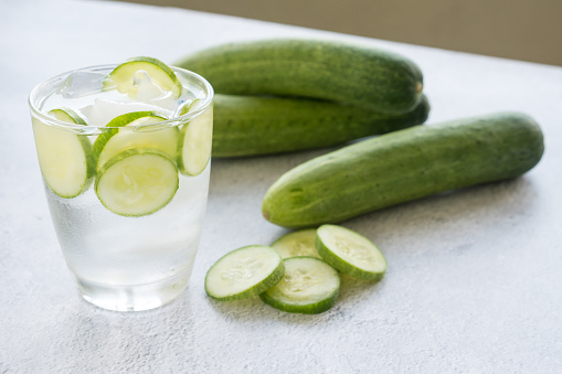 Cold water with cucumber and ice in glass on the table