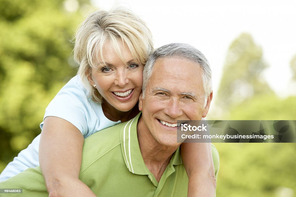 Senior man giving senior woman a piggyback ride Mature couple having fun in countryside together 60-69 Years Stock Photo