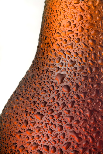 Macro of transpiration drops in a red ale beer bottle. 