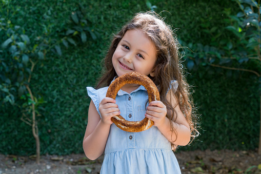 Adorable little girl holding Turkish Bagel (simit)