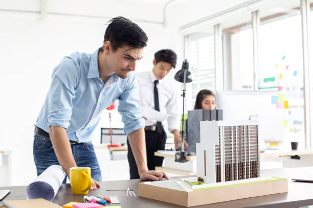 istock Male architect looking to condominium model with serious emotion. 984719526