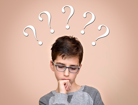 Thinking cute young boy with five question marks above his head