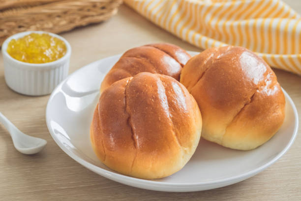 круглая булочка, булочки на белой тарелке и ананасовое варенье - bun с�токовые фото и изображения