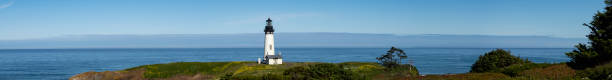 Yaquina Head Lighthouse on the Pacific Ocean in Oregon. Panoramic. This is near the town of Newport, Oregon. This is a historic area from the mid 1800's. The grassy cliff is part of Yaquina Head, a narrow headland that extends into the Ocean.