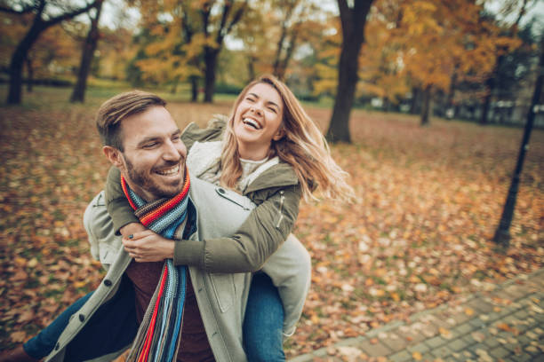 istock Young cheerful couple having fun while piggybacking in autumn day. 984746474