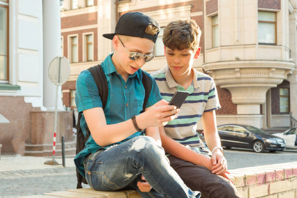 l’amitié et la communication des deux adolescents est de 13, 14 ans, fond rue ville - friendship early teens 13 14 years city street photos et images de collection