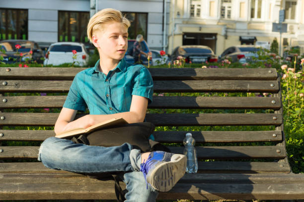 odkryty portret nastoletniego chłopca 13, 14 lat siedzącego na ławce w parku miejskim. - nature sitting 13 14 years cute zdjęcia i obrazy z banku zdjęć