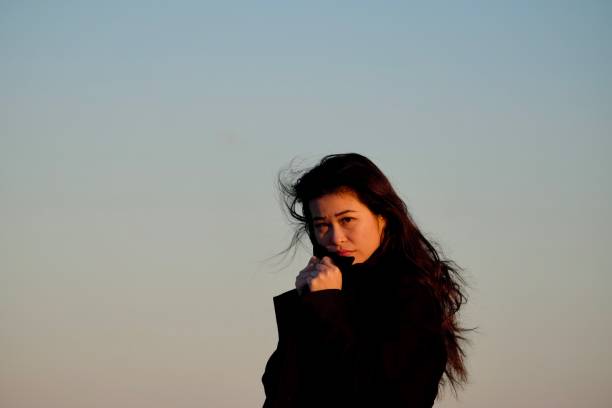 istock Chinese girl with black coat against sunset sky. 984753964