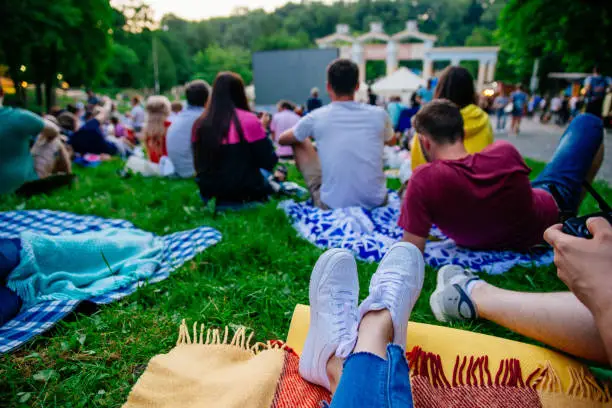 Photo of people watching movie in open air cinema in city park