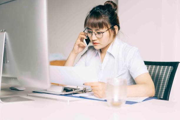 istock businesswoman talking on phone while reading files 984762652
