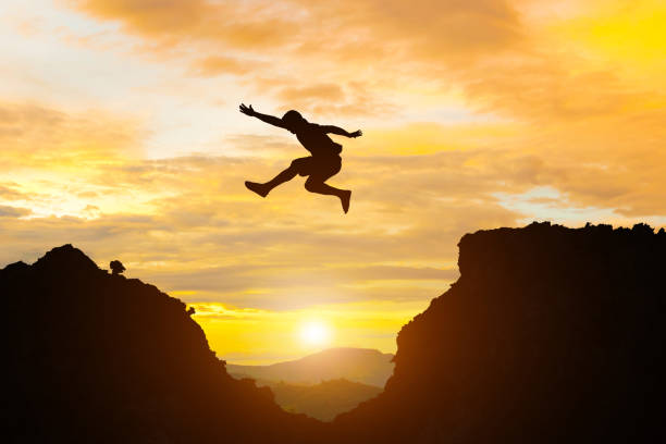 istock Man jump mountain cliff morning mountain sky and over silhouette 984766850
