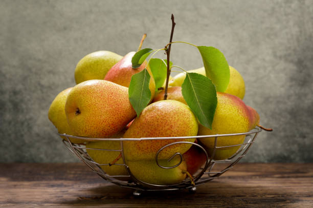 istock pears with leaves in a basket on wooden table 984767300