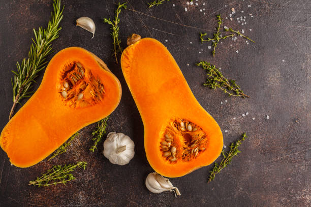 istock Raw cut pumpkin batternat with rosemary, thyme and garlic on a dark background, copy space. 984771108