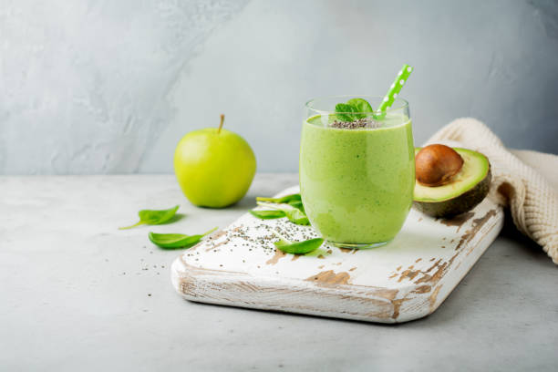 Vegetarian healthy green smoothie from avocado, spinach leaves, apple and chia seeds on gray concrete background. Selective focus. Space for text. stock photo