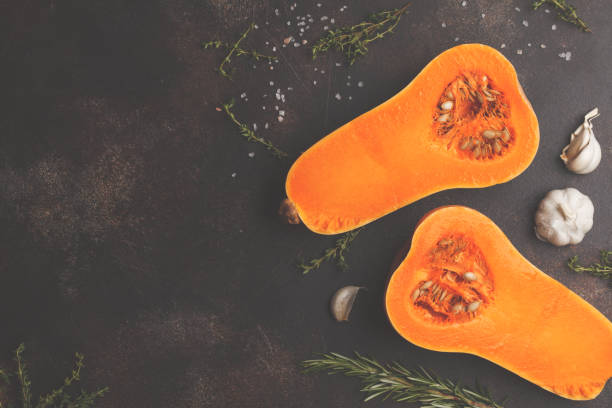 istock Raw cut pumpkin batternat with rosemary, thyme and garlic on a dark background, copy space. 984773218