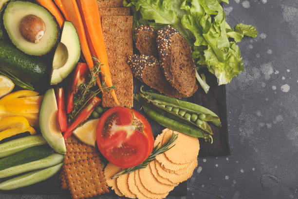 istock Vegetarian different snacks and fresh vegetables on a dark background, top view. Healthy vegan food concept. 984775414
