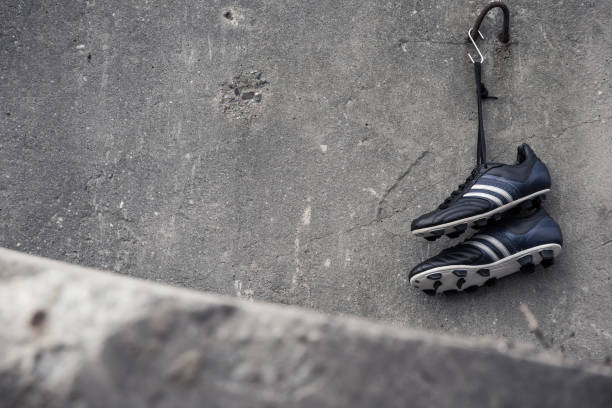 Zapatos de fútbol colgadas en una pared concreta. - foto de stock