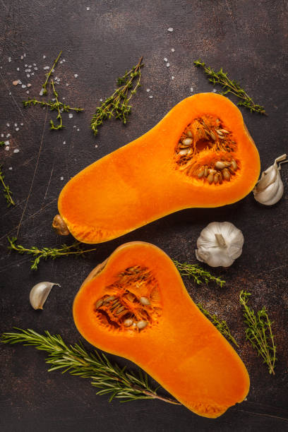 istock Raw cut pumpkin batternat with rosemary, thyme and garlic on a dark background, copy space. 984777550