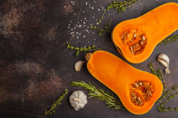 istock Raw cut pumpkin batternat with rosemary, thyme and garlic on a dark background, copy space. 984782574