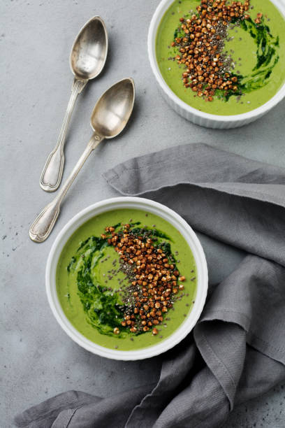istock Useful smoothies from spinach with buckwheat flakes in ceramic bowls on gray concrete table background. Selective focus. Top view. Copy space. 984787716