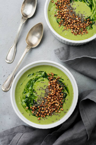 istock Useful smoothies from spinach with buckwheat flakes in ceramic bowls on gray concrete table background. Selective focus. Top view. Copy space. 984788020