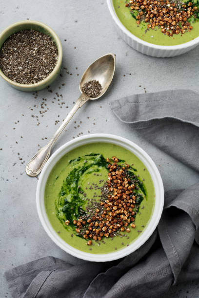 istock Useful smoothies from spinach with buckwheat flakes in ceramic bowls on gray concrete table background. Selective focus. Top view. Copy space. 984788100