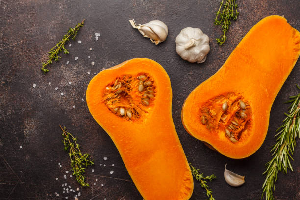 istock Raw cut pumpkin batternat with rosemary, thyme and garlic on a dark background, copy space. 984790380