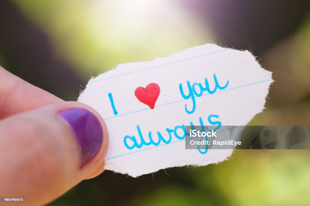 Hand holds hand-drawn "I love you always" note A female hand holds a little hand-drawn love note reading "I love you always" with love being replaced by the heart symbol. Cute Stock Photo