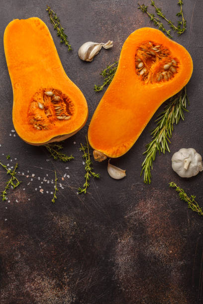 istock Raw cut pumpkin batternat with rosemary, thyme and garlic on a dark background, copy space. 984791370