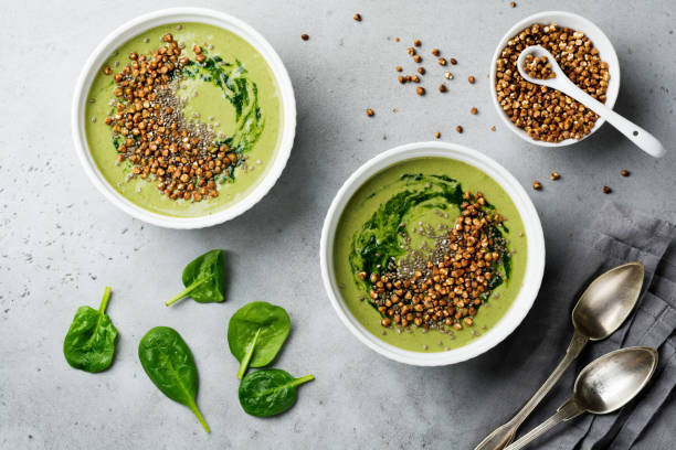 istock Useful smoothies from spinach with buckwheat flakes in ceramic bowls on gray concrete table background. Selective focus. Top view. Copy space. 984791820