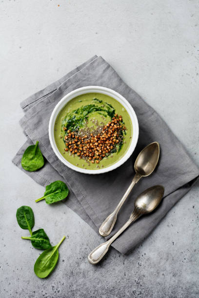 istock Useful smoothies from spinach with buckwheat flakes in ceramic bowls on gray concrete table background. Selective focus. Top view. Copy space. 984792684