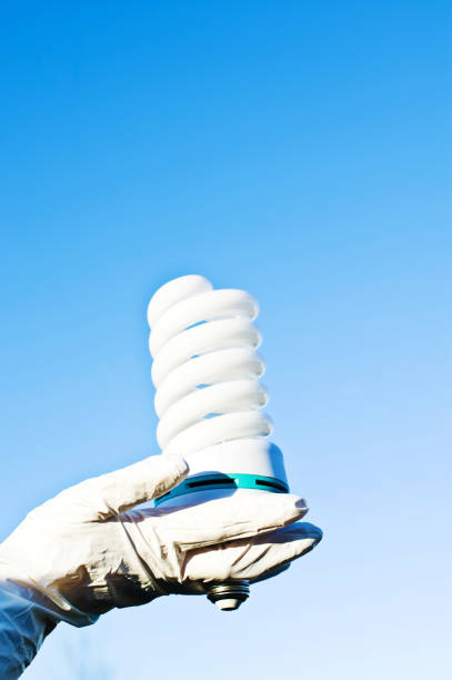 Hand In White Latex Gloves Holding Spiral Electric Lamp Bulb Hand In White Latex Gloves Holding Spiral Electric Bulb photodiode stock pictures, royalty-free photos & images