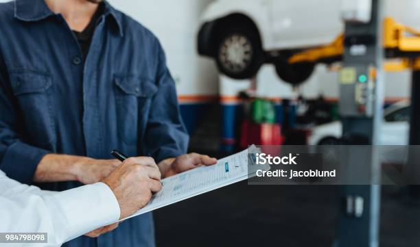 Auto Mechanic Taking Sign On Document From Customer Stock Photo - Download Image Now